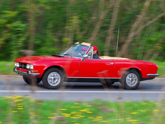 Red Peugeot convertible driving on a road