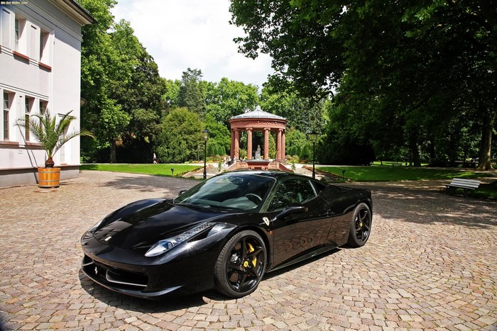 Black Ferrari parked on cobblestone driveway