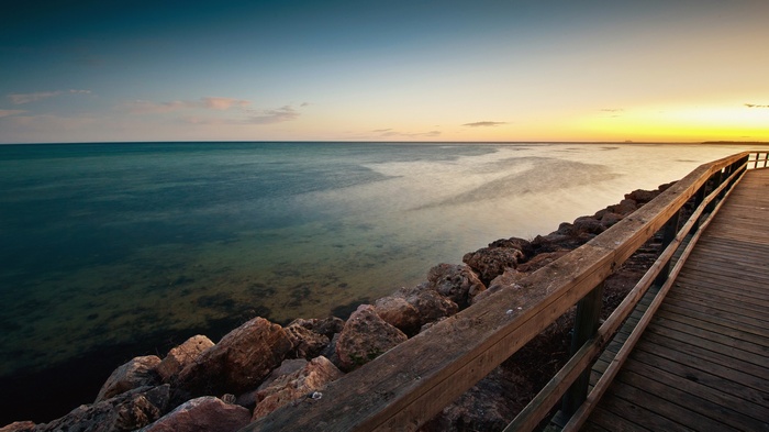 Wooden pier and rocky shore at sunset