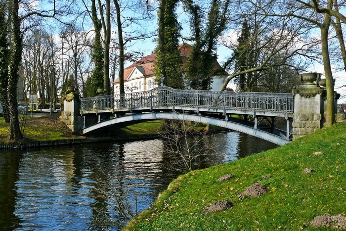 Ornate bridge over a canal with a building in the background