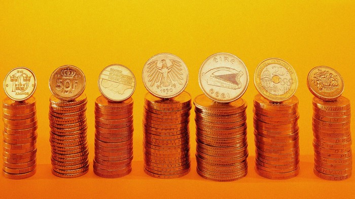 Stacks of European coins on an orange background