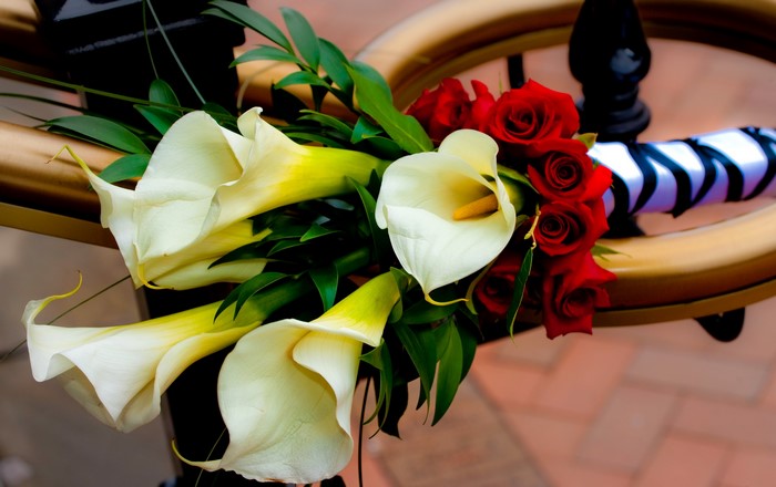 Calla lilies and red roses bouquet on a wooden structure