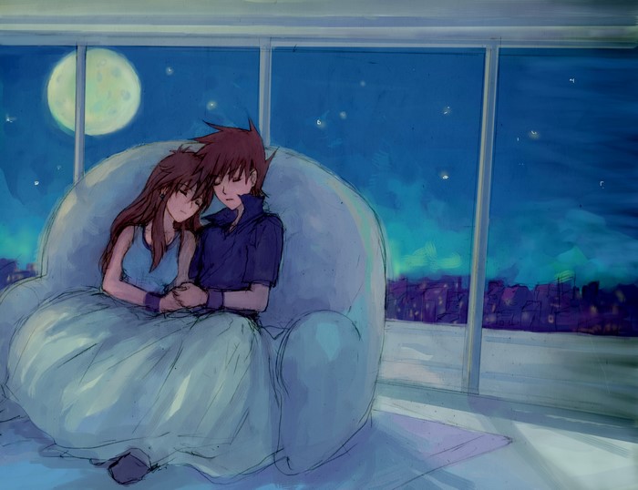 Couple cuddling on a couch overlooking a city at night