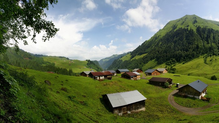 Alpine village with green mountains and clouds