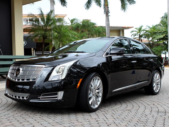 Black Cadillac sedan parked on cobblestone