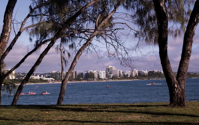 View of buildings and ocean with people in kayaks