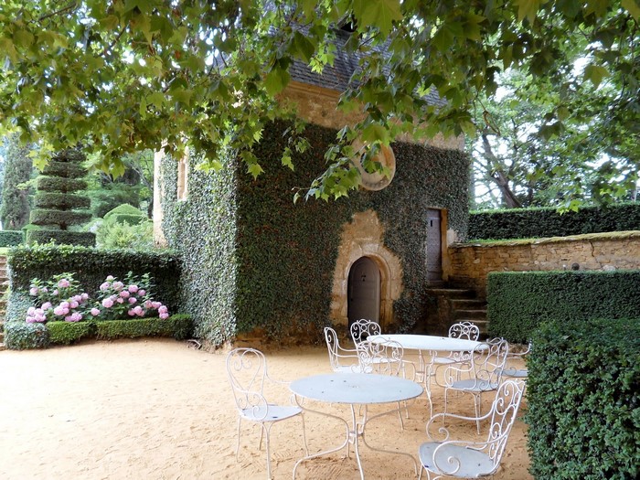 Outdoor cafe seating in a garden with ivy-covered building