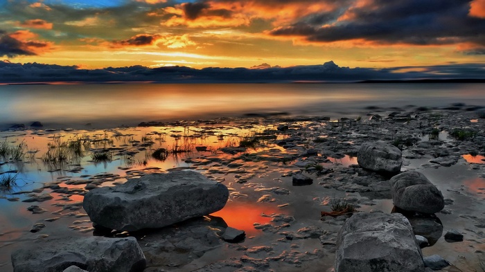 Sunset over rocky shore with calm water