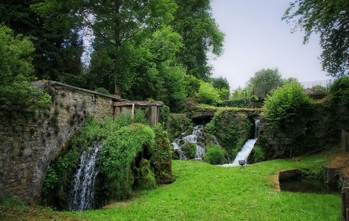 Waterfalls cascading over stone structures in a green park