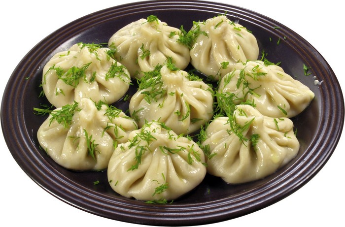 Khinkali dumplings with dill on a dark plate