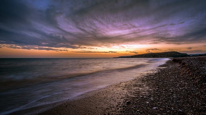 Sunset over a pebble beach and the sea