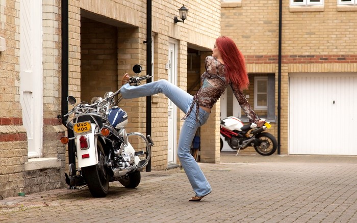 Piper Fawn with red hair kicking a motorcycle