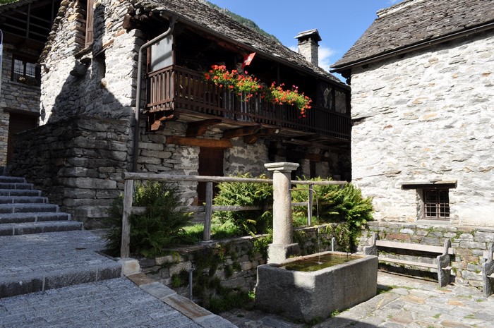 Stone houses with balcony and fountain in Sonogno, Switzerland