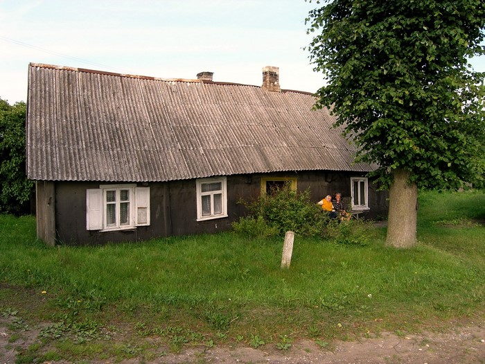 Two people sitting on a bench outside a rustic house