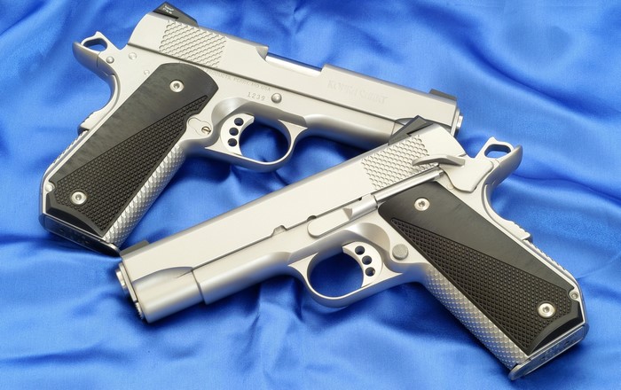 Two Colt M1911 pistols on blue fabric