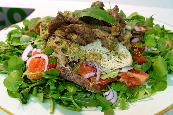 Beef and noodle salad with greens and red onion