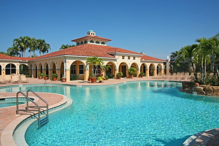 Resort pool with Mediterranean-style building and palm trees