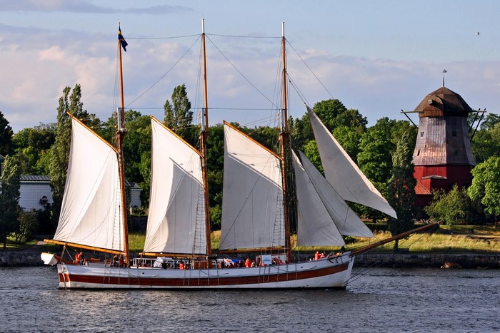 Sailboat with white sails near a red windmill