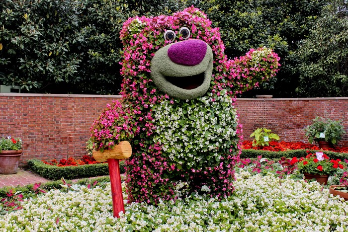 Bear topiary with flowers and a brick wall
