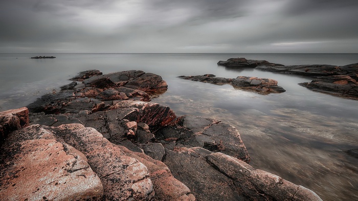 Rocky coastline with calm water under cloudy sky