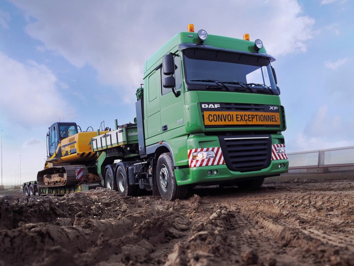 Green DAF XF truck carrying an excavator