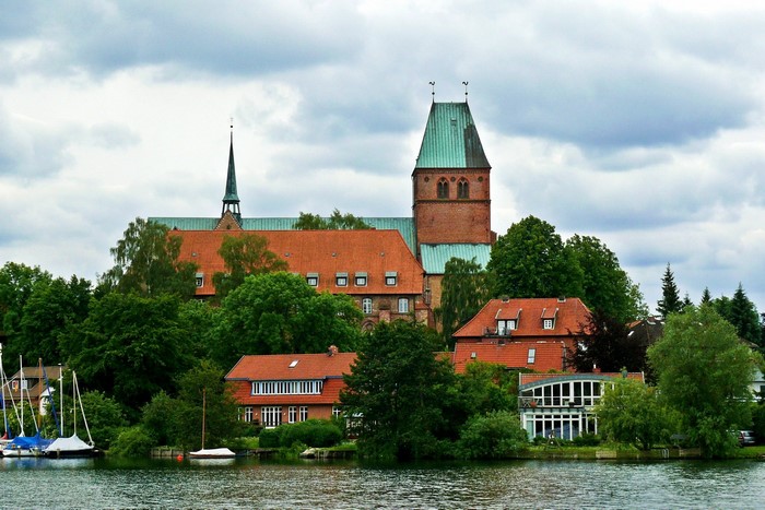 Brick church with green roof by a lake in Germany