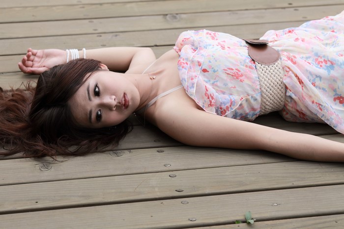 Asian woman in floral dress lying on wooden deck