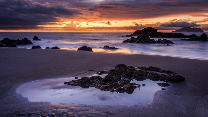 Beach with rocks and sunset over the ocean