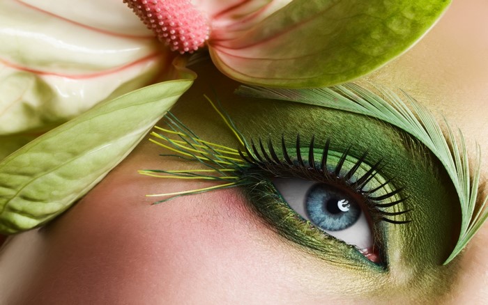 Close-up of a woman's eye with green makeup and flowers