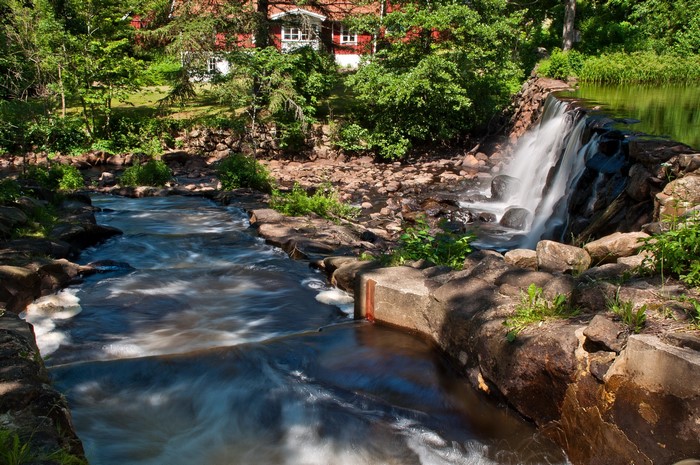 Waterfall flowing near a red house in a forest