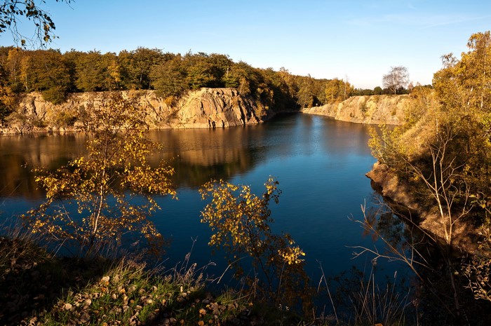 Autumn quarry lake with rocky shores and trees