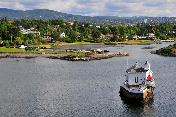 Small white building on a rock in the water, Norway