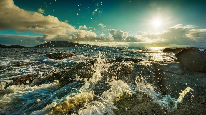 Waves crashing on rocks at sunset