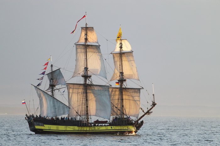 Tall ship sailing on the ocean with sails full
