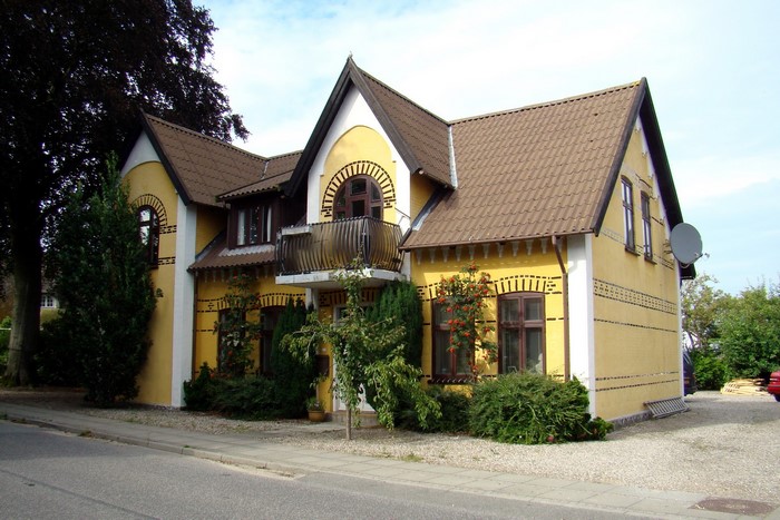 Yellow house in Denmark with arched windows and balcony