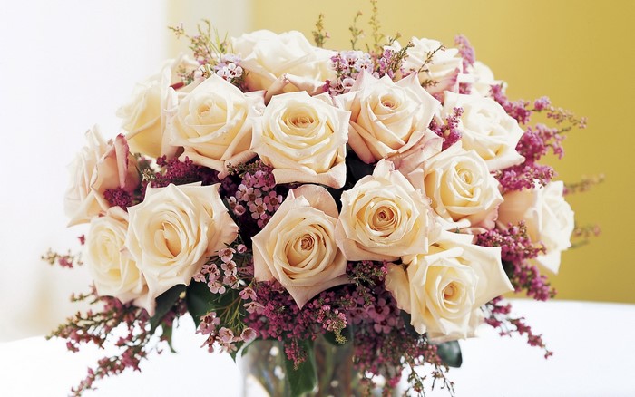 Cream roses and purple filler flowers in a bouquet