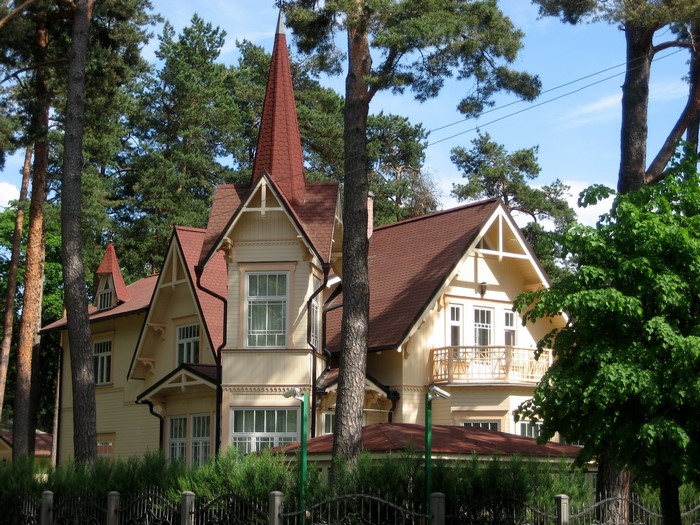 Yellow wooden house with red roof surrounded by trees