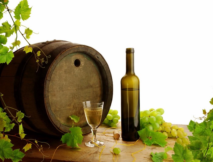 Wine barrel, bottle, glass, and grapes on a wooden table