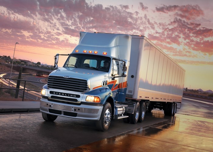 Sterling Trucks tractor-trailer on a wet road at sunset
