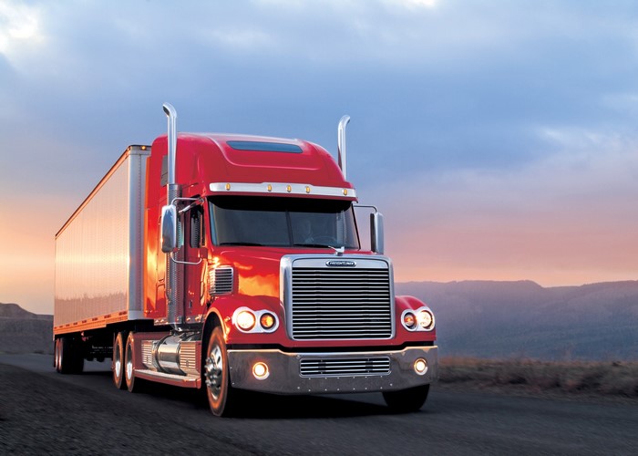 Red Freightliner Semi-Truck Driving on Road at Sunset
