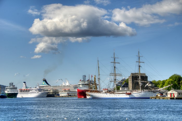 Ships docked in a harbor under a cloudy sky