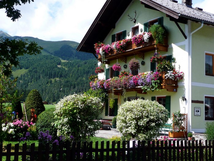 Traditional Austrian house with flower-filled balconies and mountain backdrop