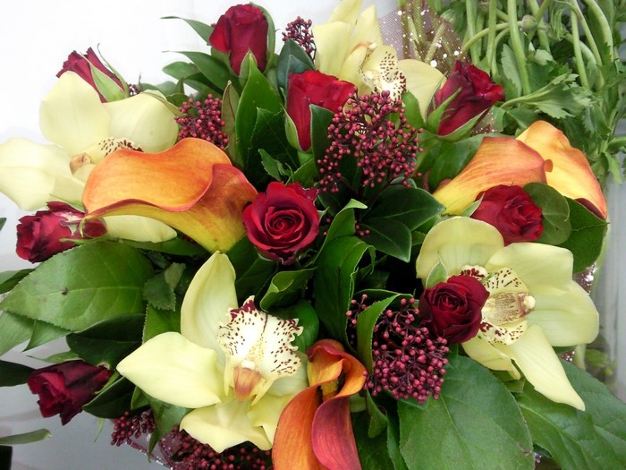 Bouquet of red roses, yellow orchids, and orange calla lilies