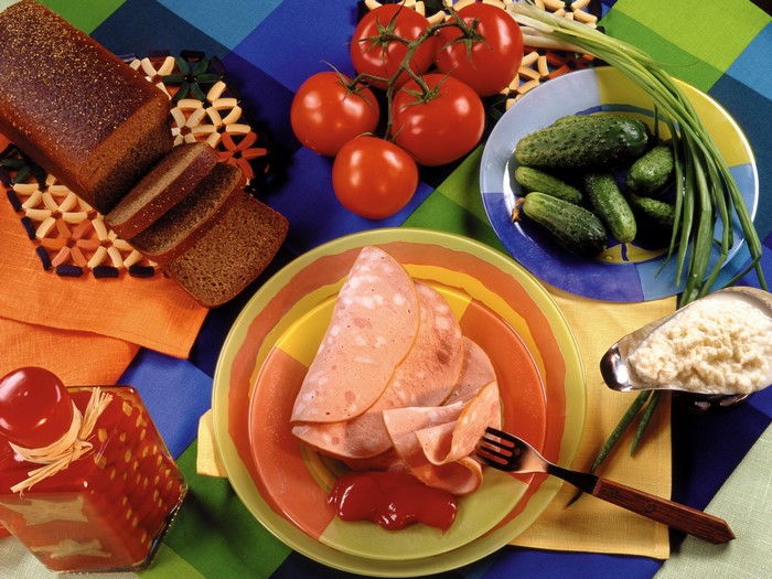 Sausage slices with ketchup, bread, tomatoes, cucumbers, and green onions