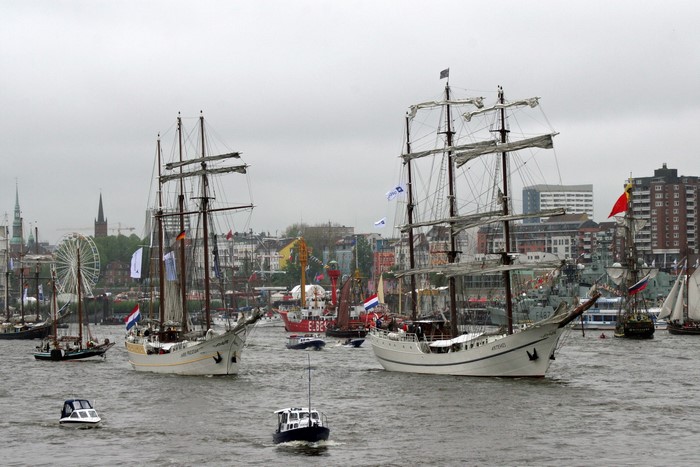 Tall ships sailing in a harbor with city skyline