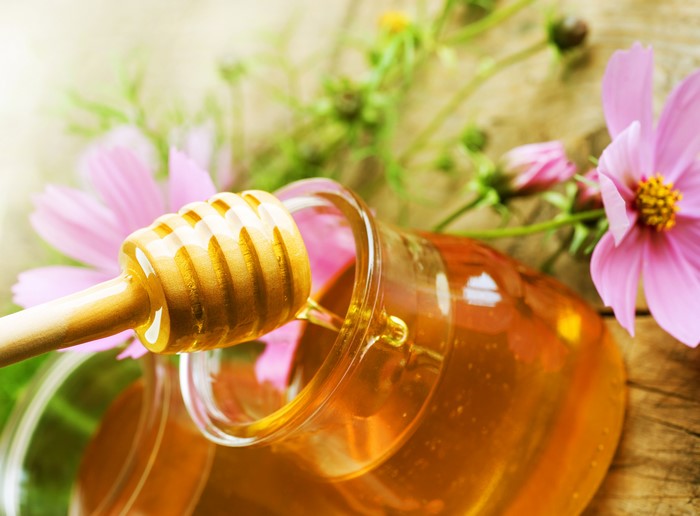 Honey dipper with honey and pink flowers