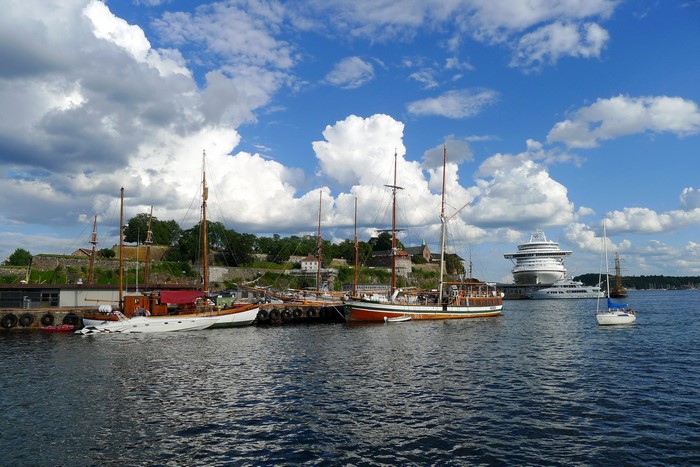 Boats docked in Oslo harbor with a cruise ship in the background