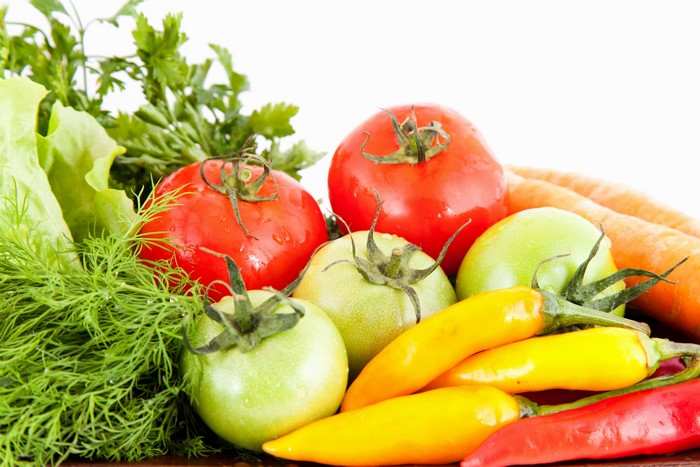 Assortment of fresh vegetables including tomatoes, peppers, carrots, and herbs