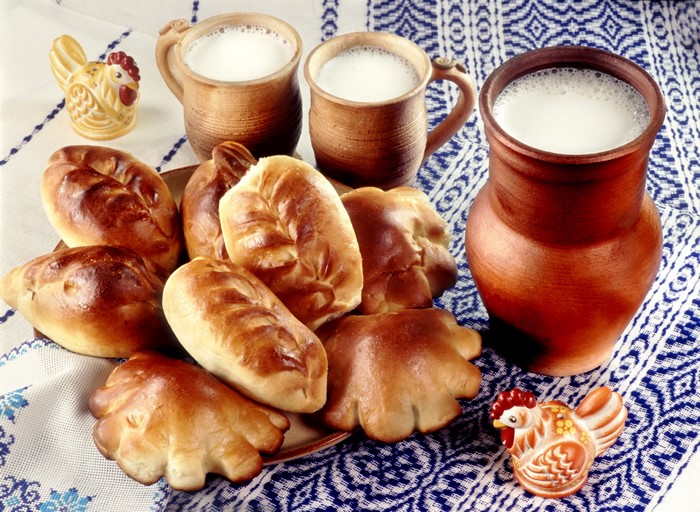 Baked pastries and milk in clay jugs and mugs
