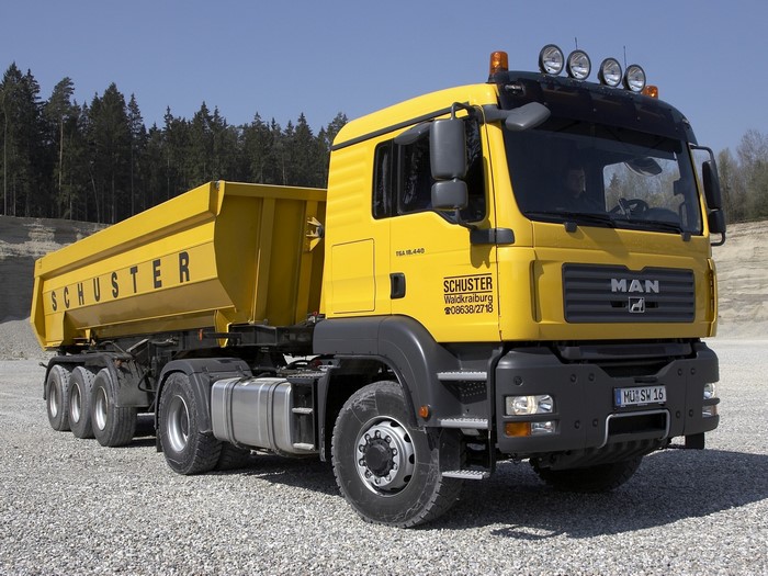 Yellow MAN TGA 18.440 dump truck with Schuster logo
